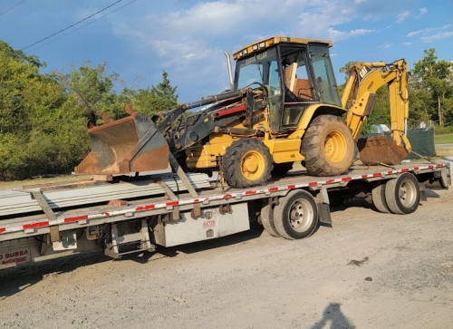 2003 Caterpillar 420D Backhoe being hauled on a step deck trailer.