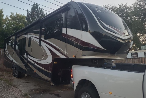 2021 Grand Design Solitude transport towed by a pickup truck using a fifth-wheel hitch.