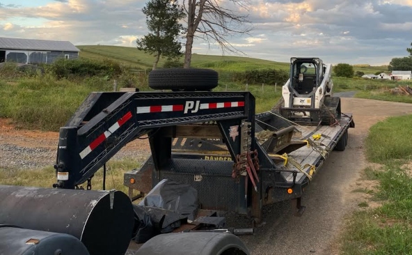 Transporting a Bobcat T770 loaded with attachments on a gooseneck trailer.