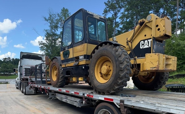 Hauling a Caterpillar TH63 telehandler on a step deck trailer.