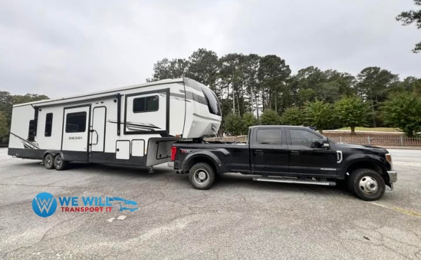 Forest River Sierra fifth wheel being transported by a specialized fifth-wheel hitch pulled by a heavy-duty truck.