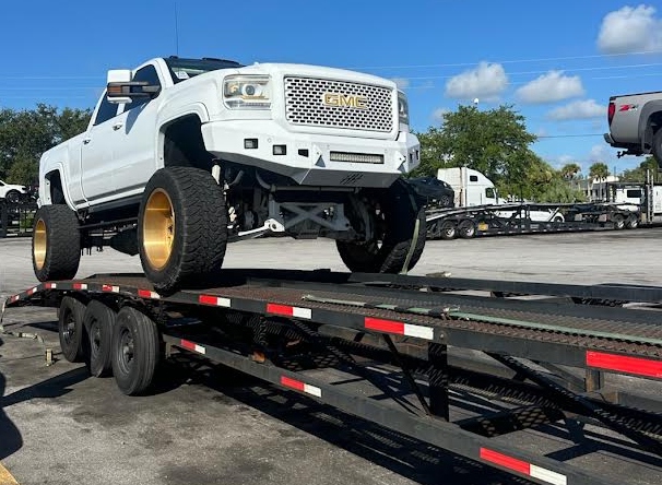 Transporting a GMC Sierra 2500HD on a two-car wedge trailer.