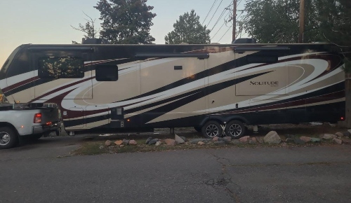Pickup truck towing a Grand Design Solitude fifth wheel RV.