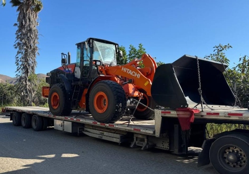Hauling a Hitachi ZW180-6 wheel loader on a step deck trailer.