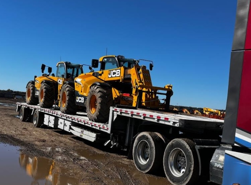 JCB telehandler transported on a step deck trailer.