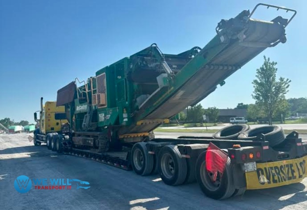 Hauling a McCloskey Heavy-Duty Mobile Jaw Crusher on a lowboy trailer with a oversize banner in the back of the trailer from Madison, Wisconsin to Norman, Oklahoma.