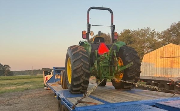 Hauling a John Deere 5065 E tractor on a gooseneck flatbed trailer.