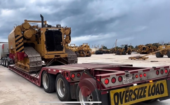 Moving a Caterpillar D11 dozer on a lowboy trailer with a oversize banner on the back of the trailer.