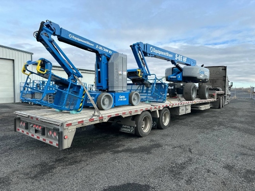 Moving two Genie S-65 HF Telescopic Boom Lift on a step deck trailer.
