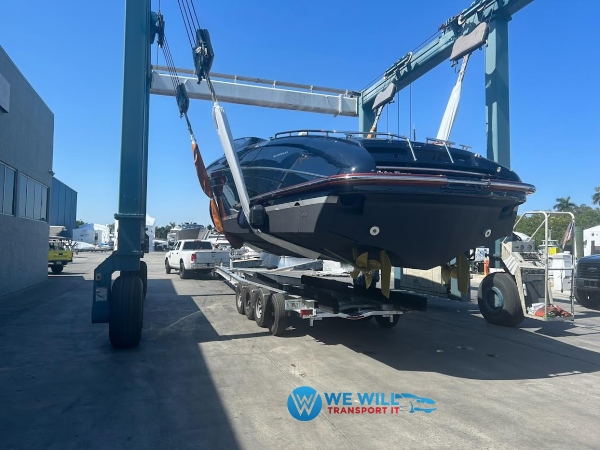 Travel lift lowering a Riva Rivamare 38 luxury motor yacht onto a triple-axle boat trailer for transport from Cary, North Carolina to Springfield, Massachusetts.