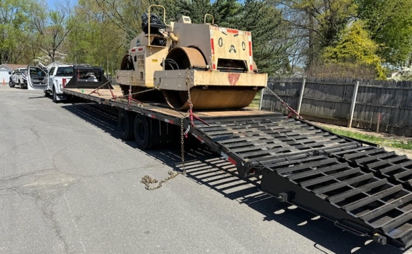 Shipping a Ingersoll-Rand DD-90HF double drum roller on a gooseneck flatbed with loading ramps.