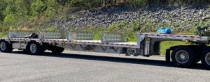 Step deck trailer hauling mid-sized equipment