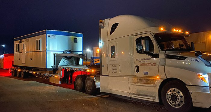 Transport-Trailers A white truck is transporting a white and blue office trailer