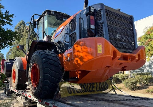 Transporting a Hitachi ZW180-6 wheel loader on a step deck trailer.