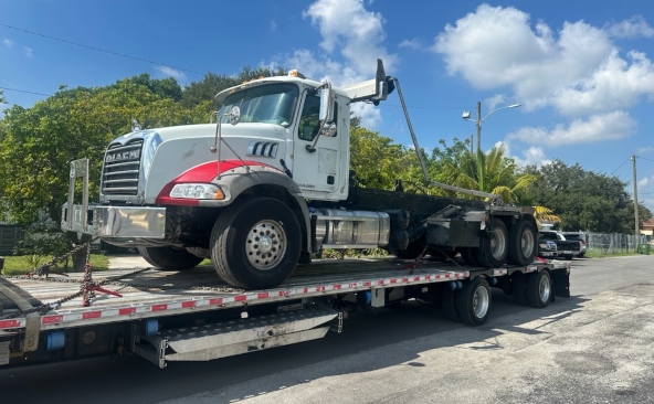 Transporting a Mack Granite hook-lift truck on a low profile step deck trailer.