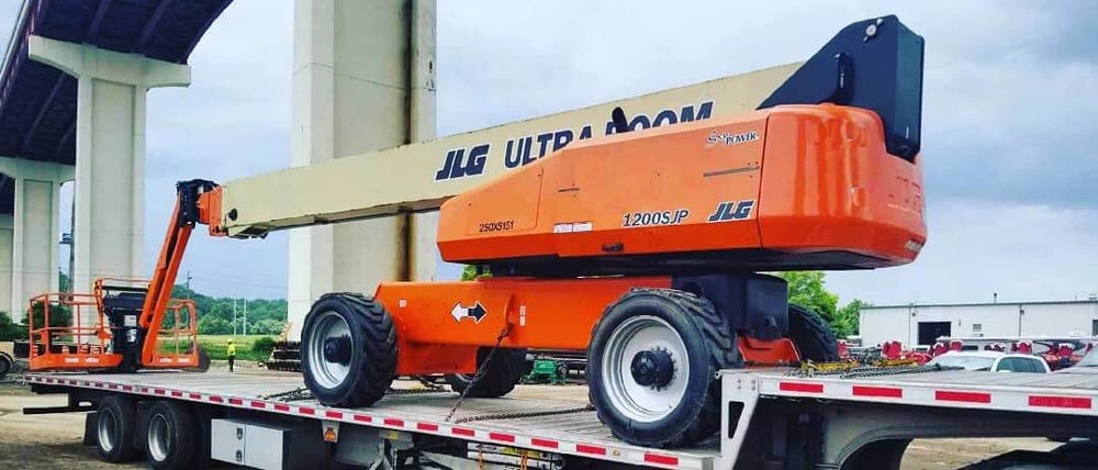 hauling a LJG 1200SJP using a flatbed trailer truck